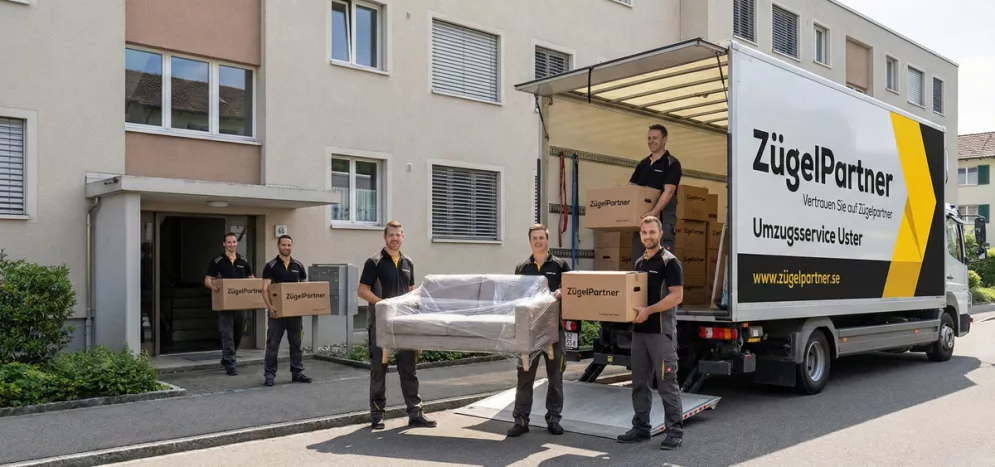 Ein freundliches Team des Umzugsunternehmens Uster trägt sorgfältig verpackte Möbelkartons aus einem Wohnhaus Ein freundliches Team des Umzugsunternehmens Uster trägt sorgfältig verpackte Möbelkartons aus einem Wohnhaus